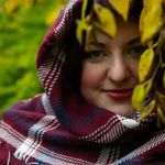 Headshot of a smiling woman with a natural background.